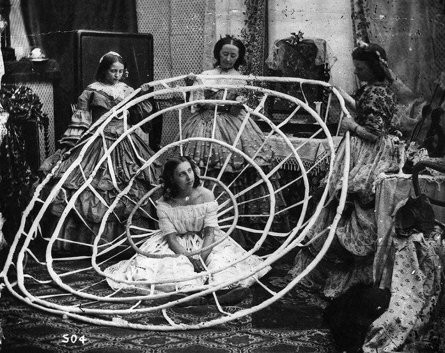 Женщина ждет, пока работницы лондонского ателье не завершат собирать обручи ее кринолина. 1860 год.