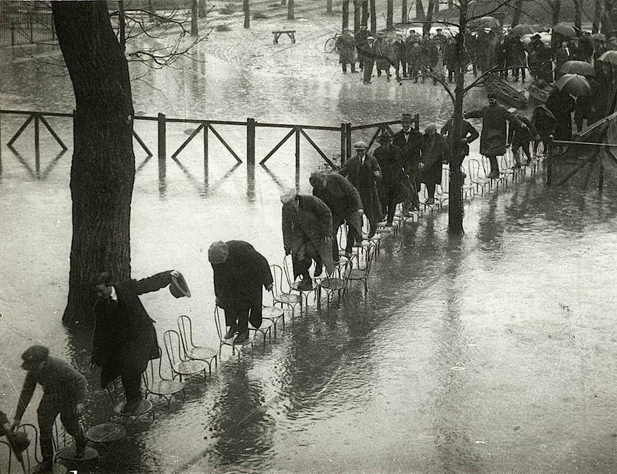  Парижане переходят затопленные улицы по стульям. 1924 год.