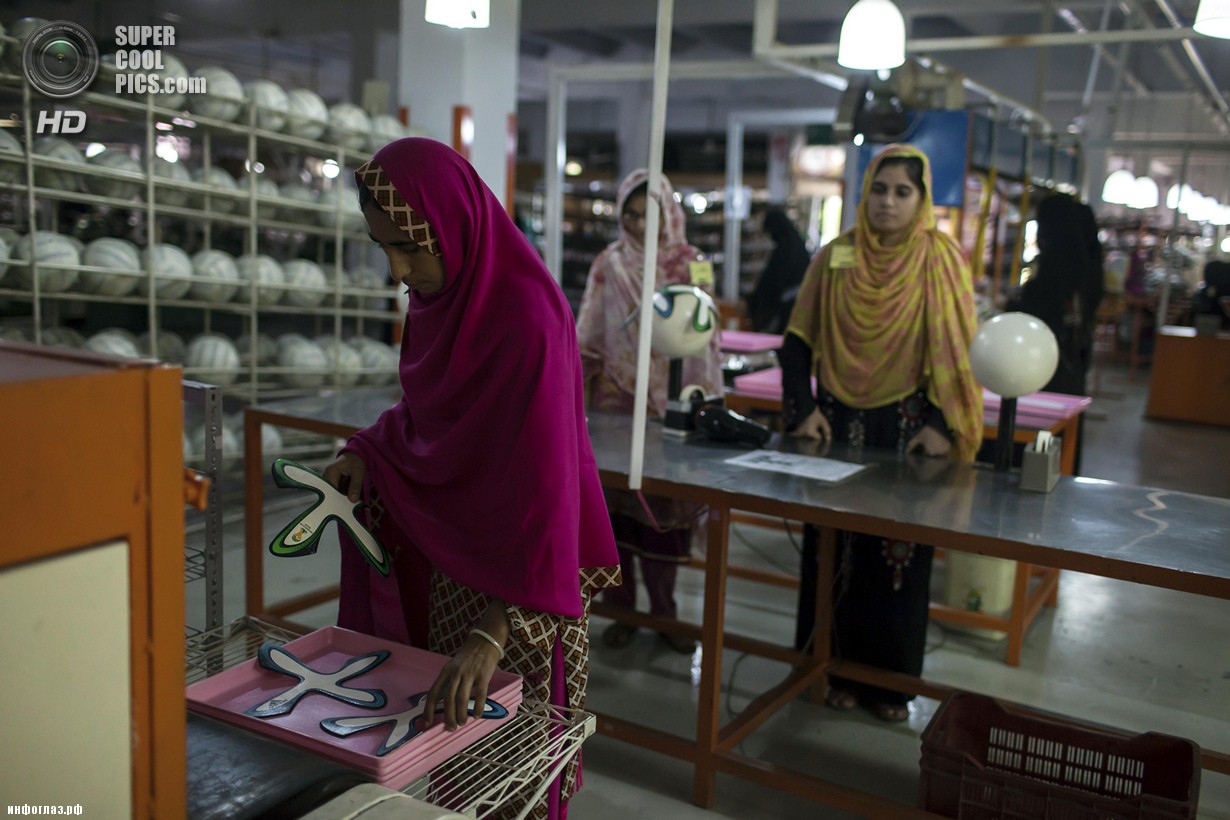 Пакистан. Сиялкот, Пенджаб. 16 мая. Работница фабрики вынимает фигурные панели из машины, которая наносит клей по краям. (REUTERS/Sara Farid)