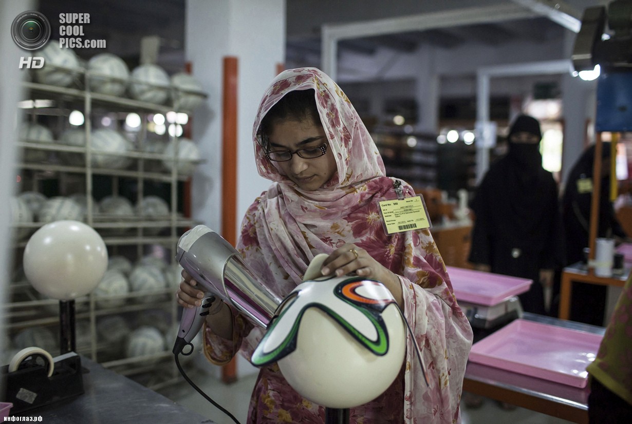 Пакистан. Сиялкот, Пенджаб. 16 мая. Работница фабрики использует фен для быстрого высушивания клея. (REUTERS/Sara Farid)